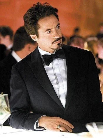Hombre elegante con esmoquin negro, camisa blanca y pajarita negra en evento formal