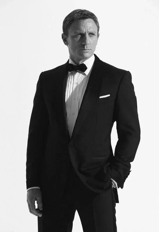Hombre elegante con pajarita negra y esmoquin en fondo blanco, estilo formal y protocolo