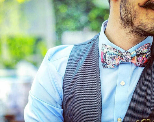 Hombre con camisa azul, chaleco gris y pajarita original con estampado de cómic, complementos frikis